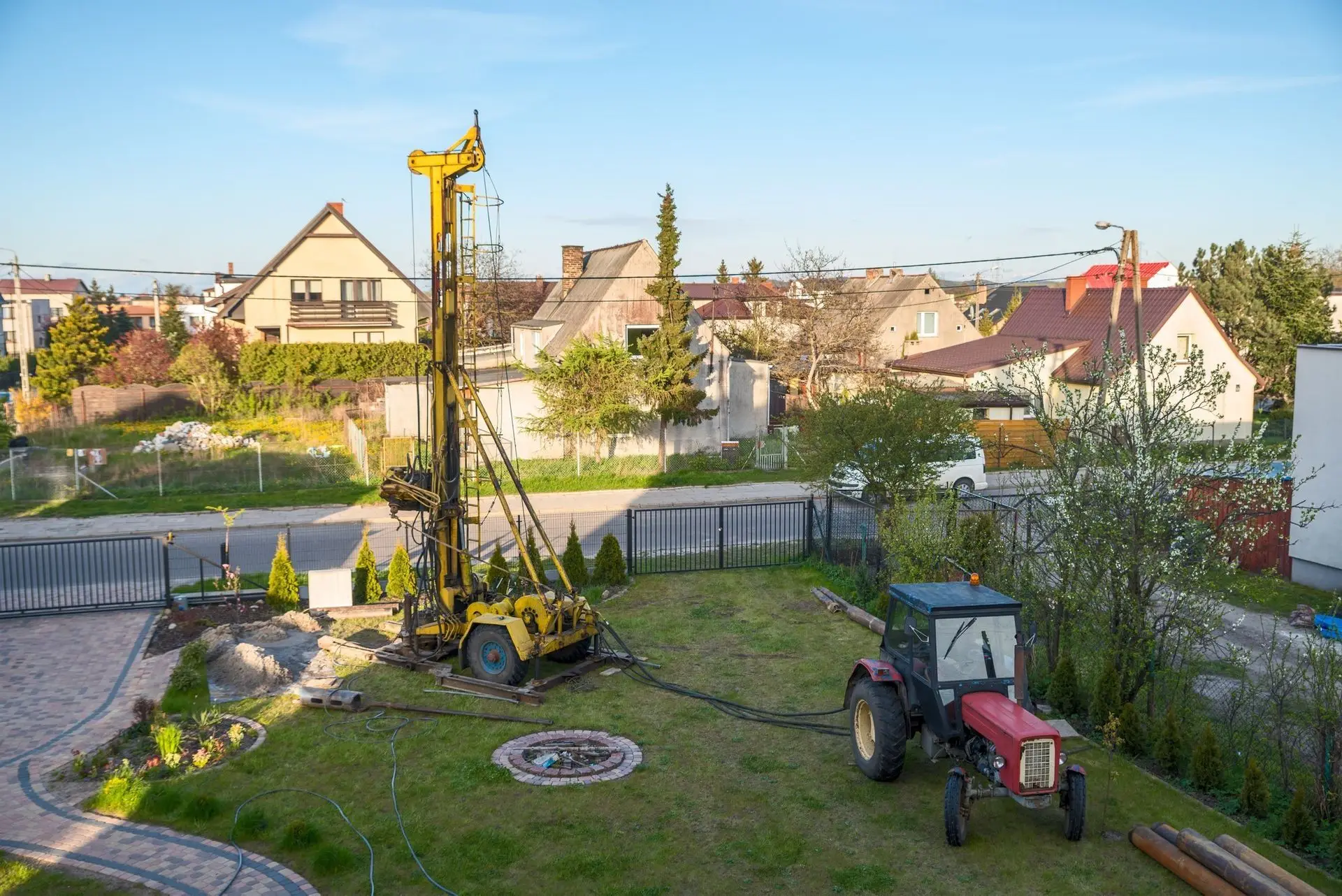 Modern yellow rotary drill providing well services at a residential site.