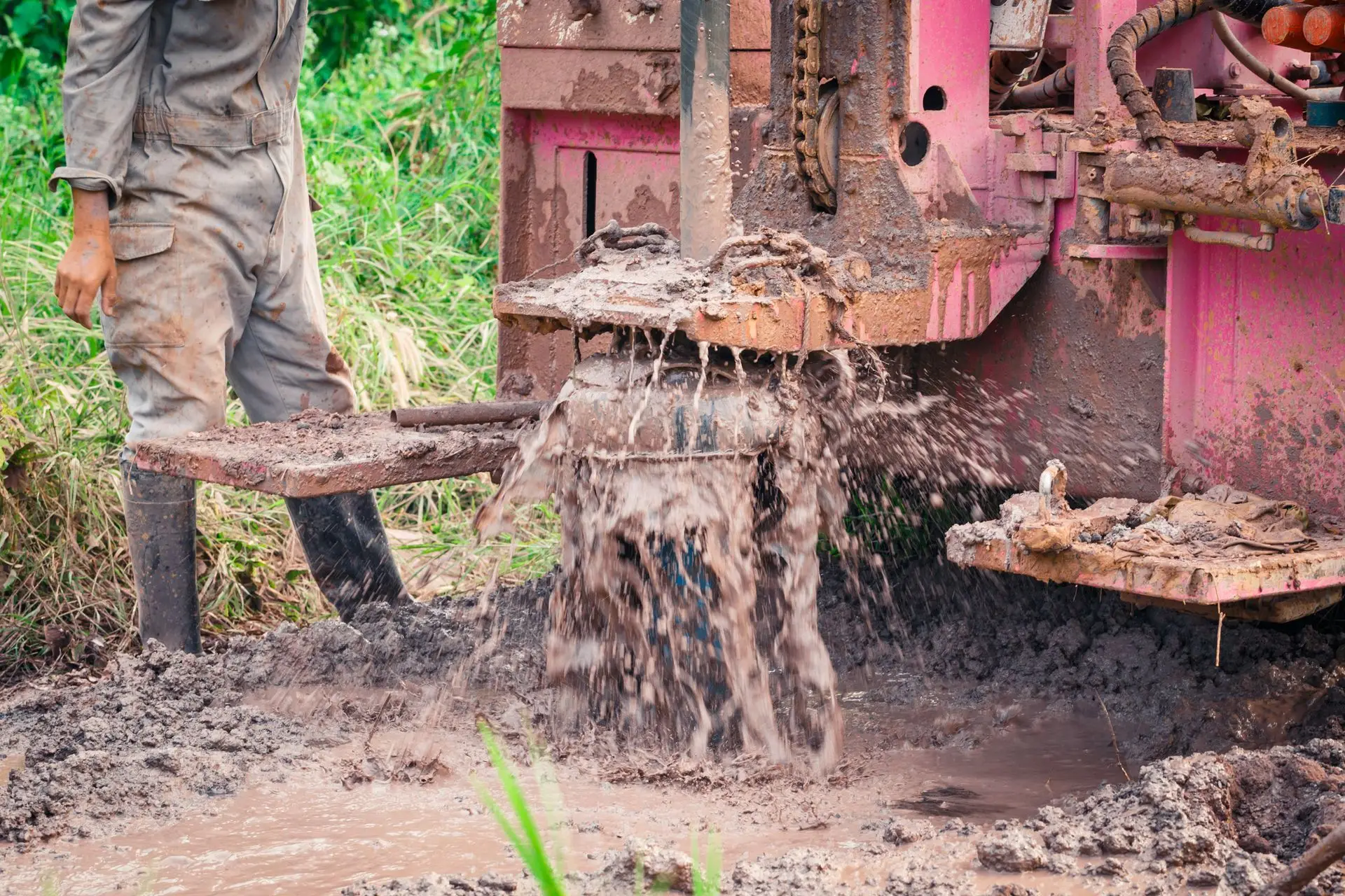 A well drilling company worker operates a large industrial drilling machine for water extraction.