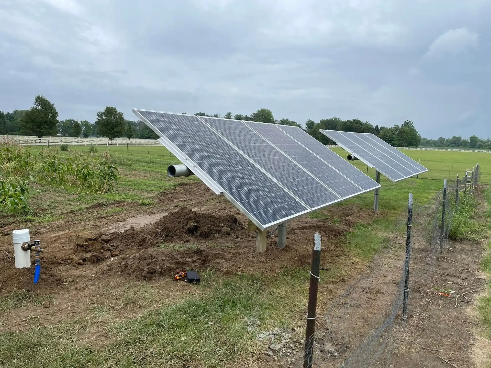 Ground-mounted solar array powering an irrigation well pump on farmland.