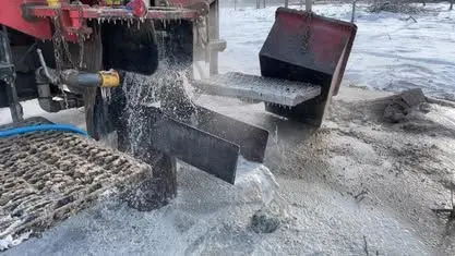 Water flushing from a drill pipe during well development on a snowy job site