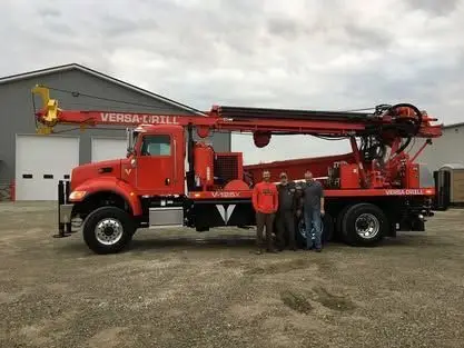 Three Wiley Well Drilling crew members beside a new red Versa-Drill rig truck