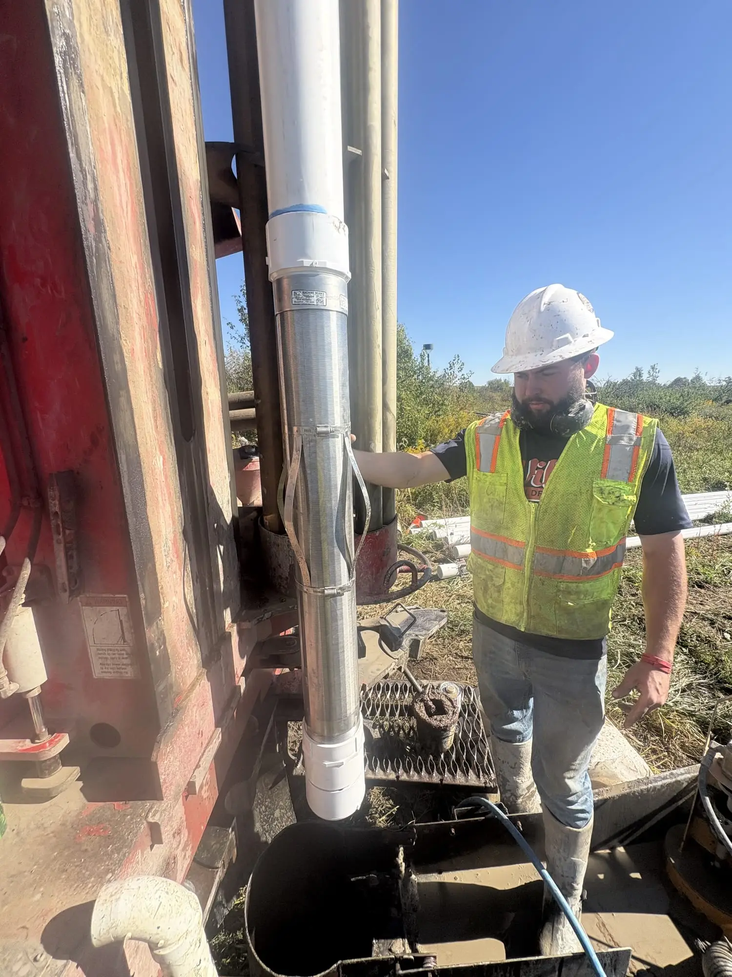 A Wiley Well Drilling crew member in a hard hat setting steel well casing at the rig.