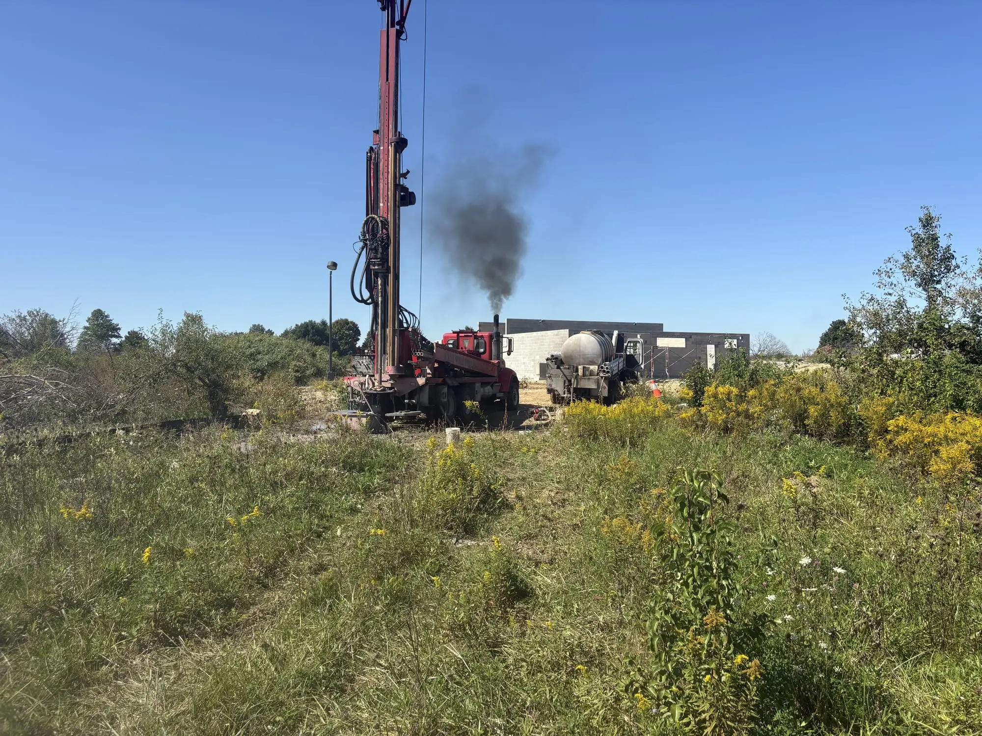 Wiley Well Drilling rig drilling a new well beside a commercial building