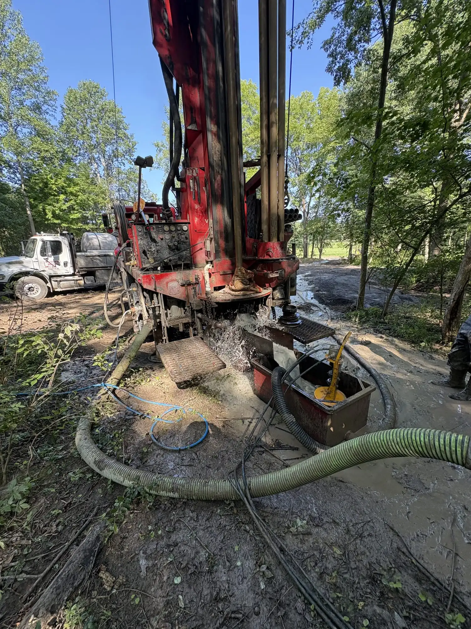 A Wiley Well Drilling rig and support truck set up at a residential well site