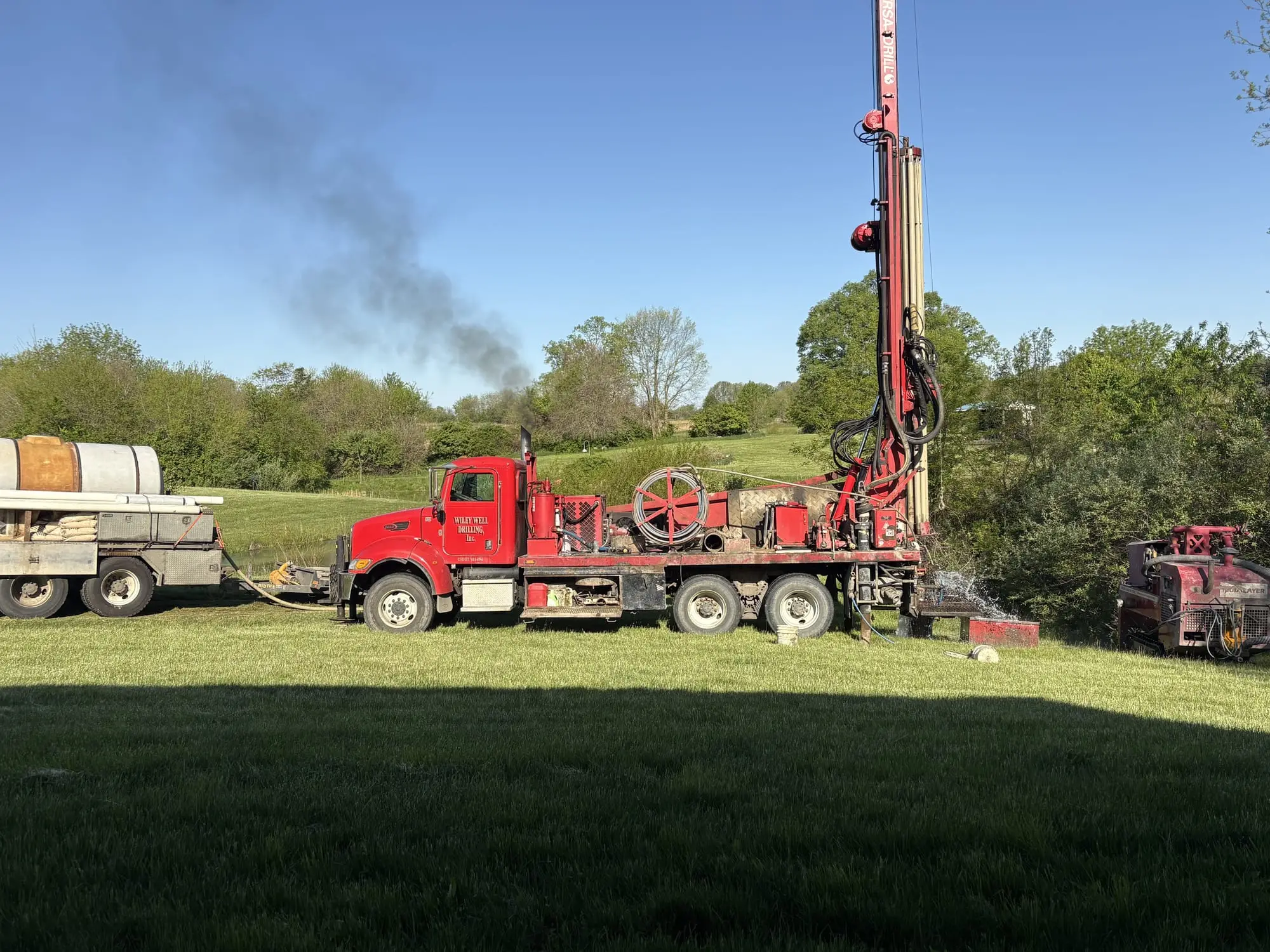 Wiley Well Drilling rig truck and water truck set up on a well site in an open field